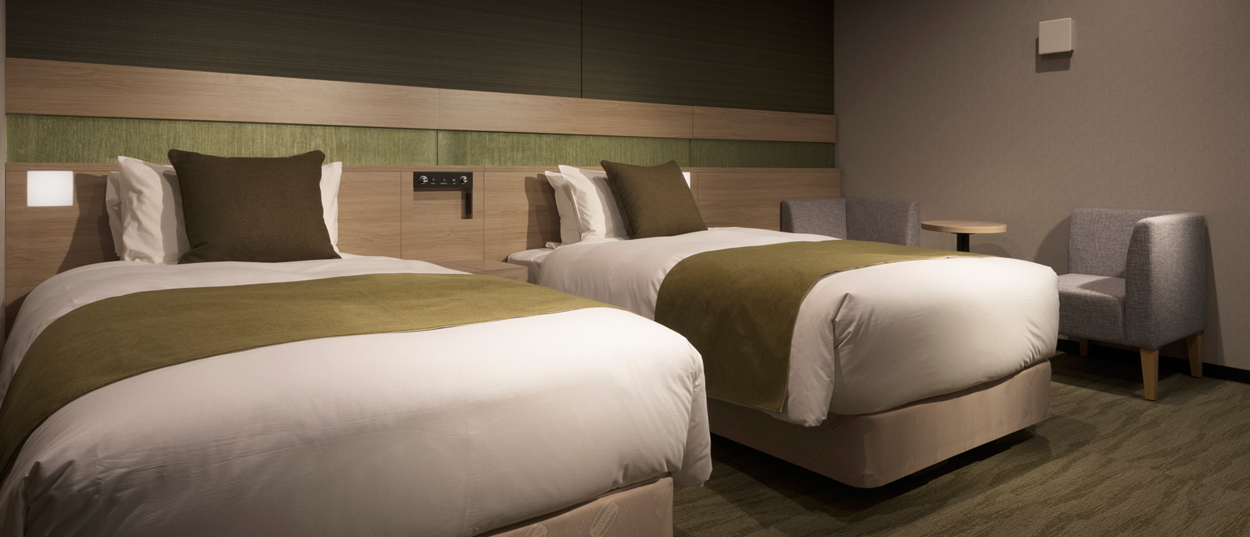 Twin room (~18㎡) with two single beds and minimalist wood-and-concrete interior