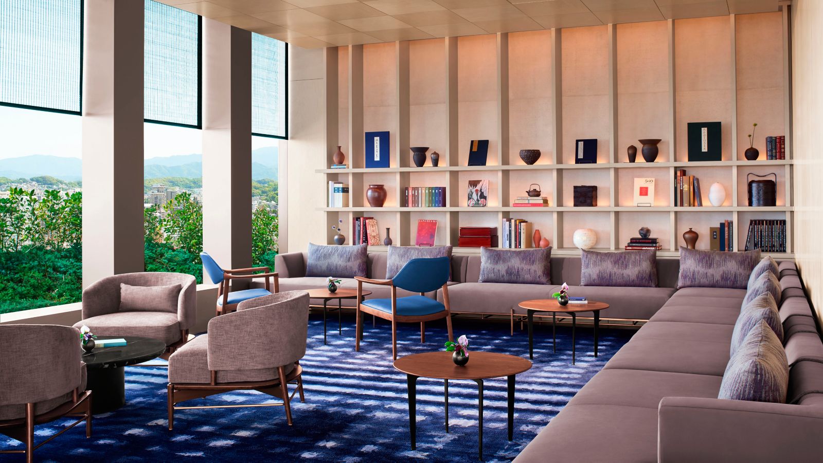 Ritz-Carlton Club Lounge library area with curated bookshelf, blue ikat-pattern carpet, and park view windows